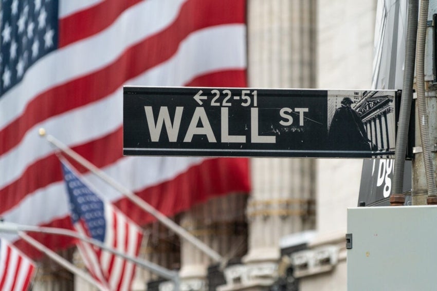 Close-Up Of Wall Street Sign With Iconic New York Skyscraper Backdrop