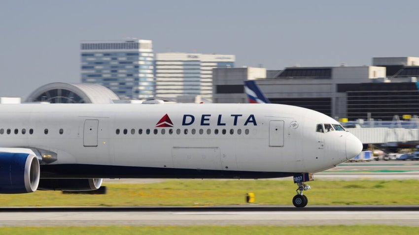 Delta plane on the runway with buildings in the background.