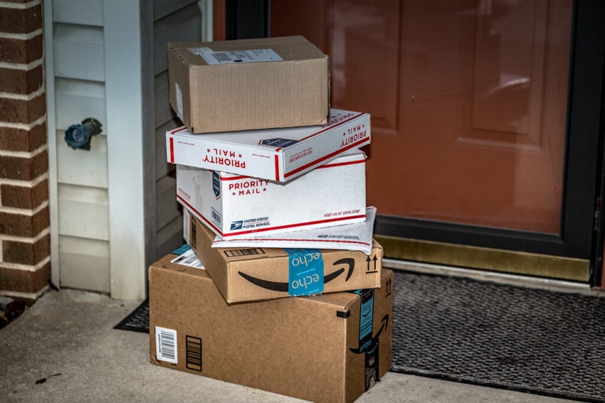 USPS, Amazon and other packages in a pile in front of a front door