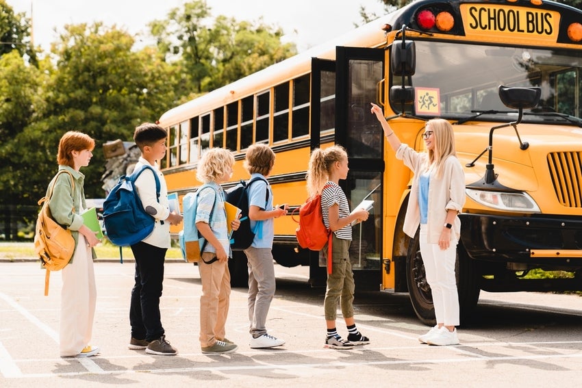 Children lined up boarding yellow school bus.