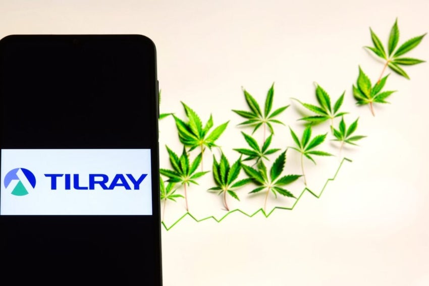 Tilray company logo on screen of smartphone against blurred background of cannabis and chart